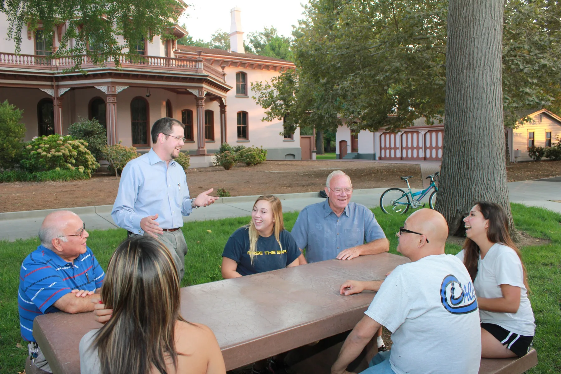 Randall Stone speaking with a group around an outdoor community table
